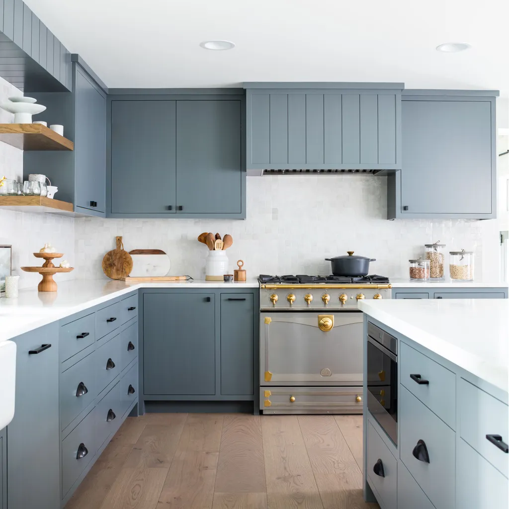 A modern kitchen with blue cabinets, white countertops, and a stainless steel oven.