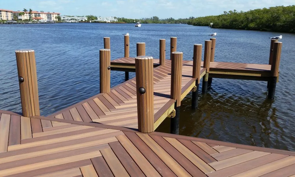 A wooden dock extends into the water with a view of the city in the distance.